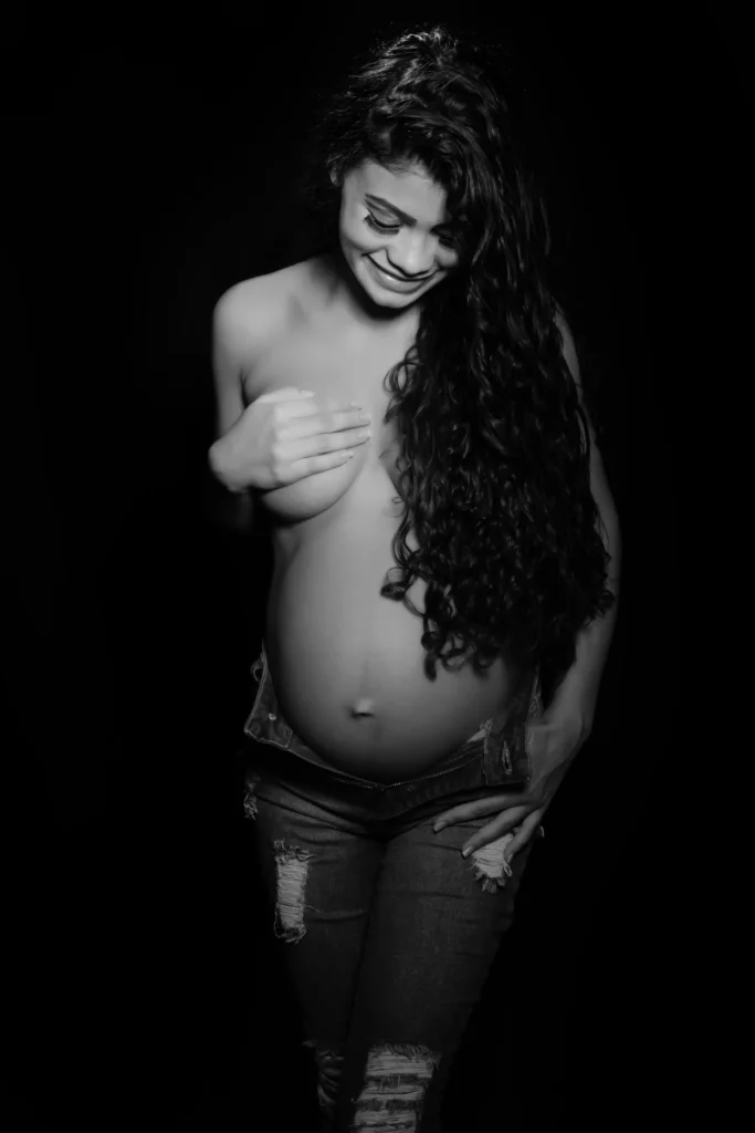 gestante em estudio em Bonsucesso com calca jeans, fundo preto